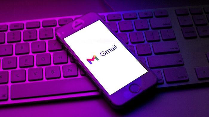 Un téléphone intelligent posé sur un clavier d'ordinateur affiche le logo de Gmail. 