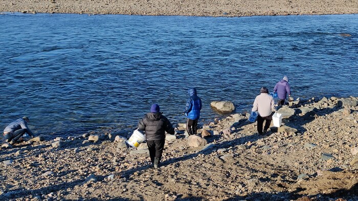Des gens puisent de l'eau dans la rivière Sylvia Grinnell, à Iqaluit, en octobre 2021.