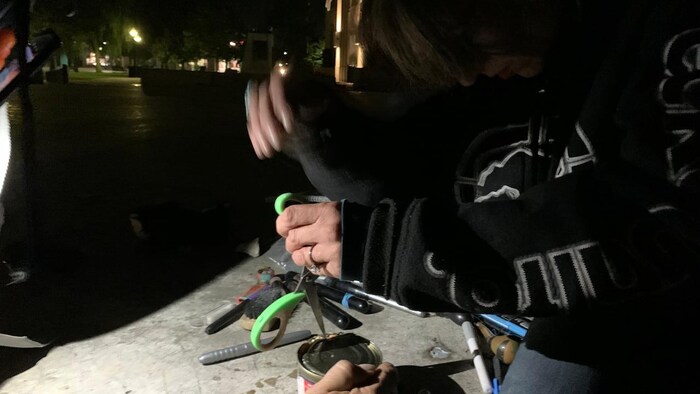 A person is trying to open a can of tinned salmon with scissors.
