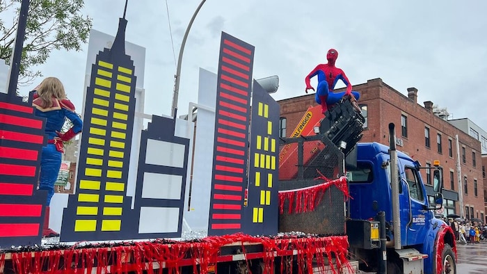 Spider-Man perché au-dessus d'un char allégorique qui défile dans la rue.
