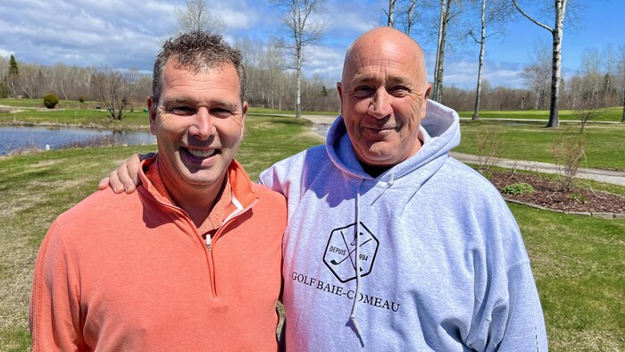 Patrick Lowe et Michel Boudreault posent devant la caméra sur un terrain de golf.
