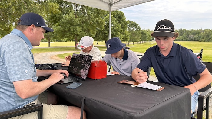 Des joueurs de golf inscrivent des informations sur une table.