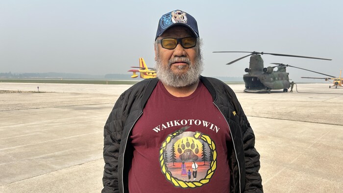 Gordie Bear est debout devant un avion militaire.