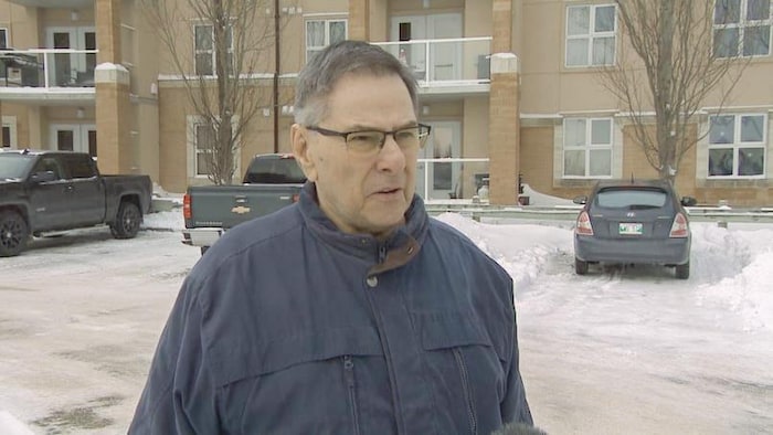 Gordon Arseny à l'extérieur durant l'hiver dans un stationnement devant un bâtiment en brique.