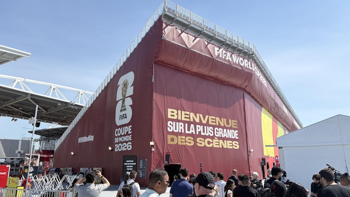 Une tribune recouverte d’un plastique rouge foncé avec le logo de la Coupe du monde et l’inscription « Bienvenue sur la plus grande des scènes ».