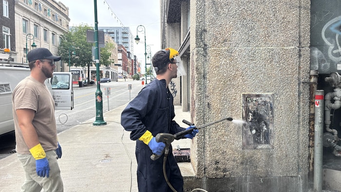 Maxime nettoie le mur avec le tuyau à haute pression.