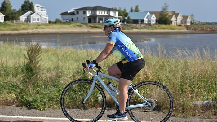 Une cycliste à vélo au bord de la mer.
