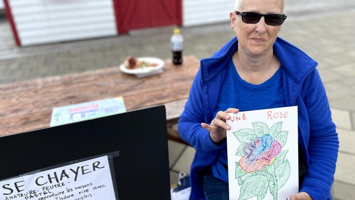 Une femme tient son dessin d'une rose.