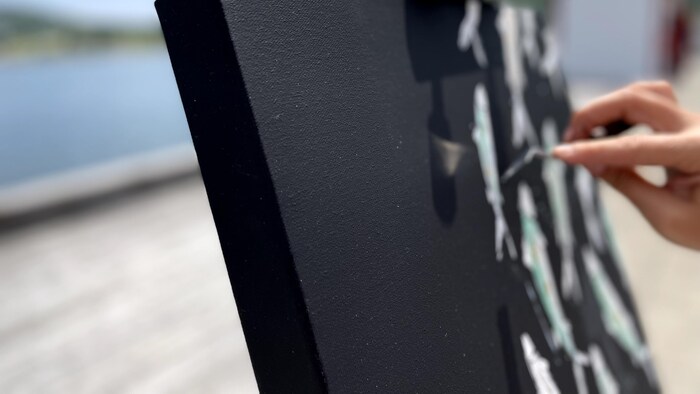 Une toile noir avec des poissons colorés.