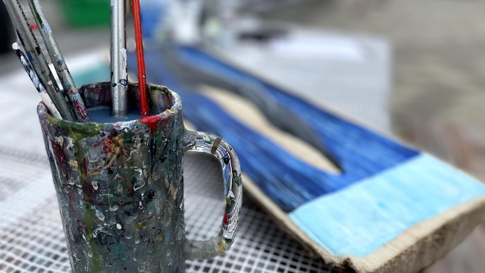 Gros plan sur une tasse sale remplie de pinceaux.