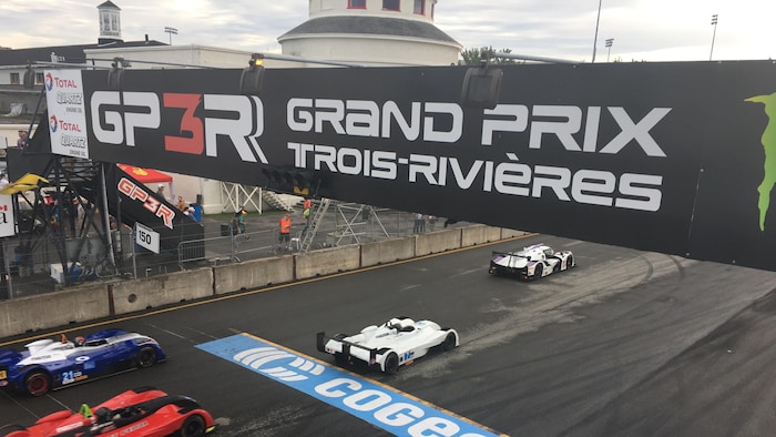 Une banderole du Grand Prix de Trois-Rivières et des voitures qui passent en dessous.