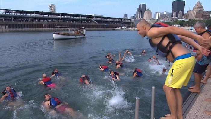 Un homme s'apprête à plonger dans les eaux du bassin Jacques-Cartier depuis le haut d'un quai dans le Vieux-Port.