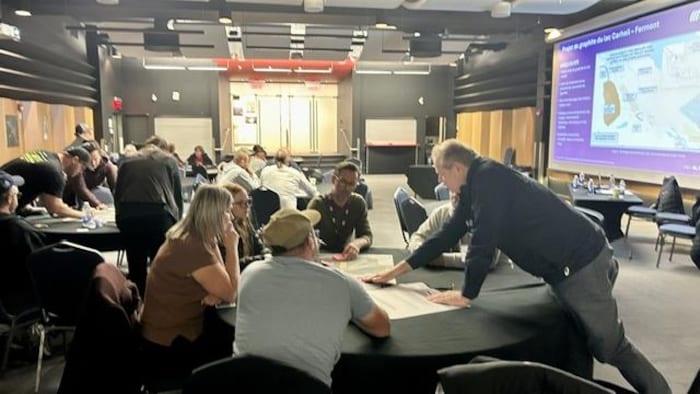 Des gens autour de plusieurs tables dans une grande salle.