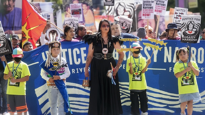 Des enfants marchent devant une banière où l'on peut lire « Justice pour Grassy Narrow ».