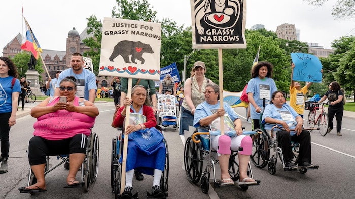 Des personnes âgées et handicapées portant des pancartes demandant justice pour la communauté autochtone.
