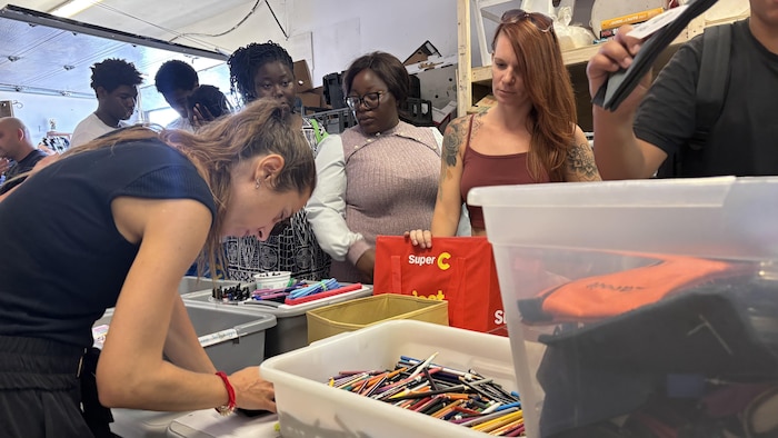 Des personnes assistent à une distribution de fournitures scolaires.