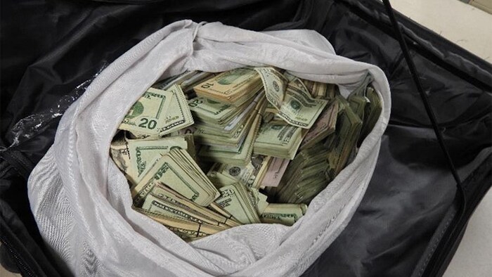 Des milliers de billets de dollars américains dans un sac.