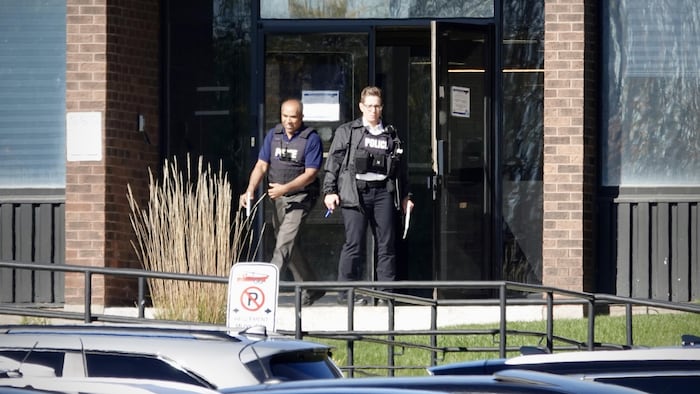 Des agents sortent d'un édifice.