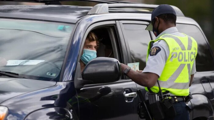 Un agent de police demande à un conducteur ses documents lors d'un contrôle lors de la pandémie.