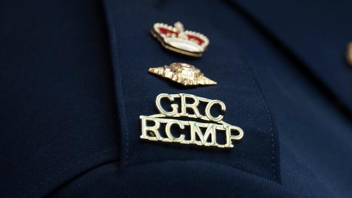  une couronne, en haut, une broche en forme de losange au milieu et une broche où il est écrit GRC RCMP en bas.