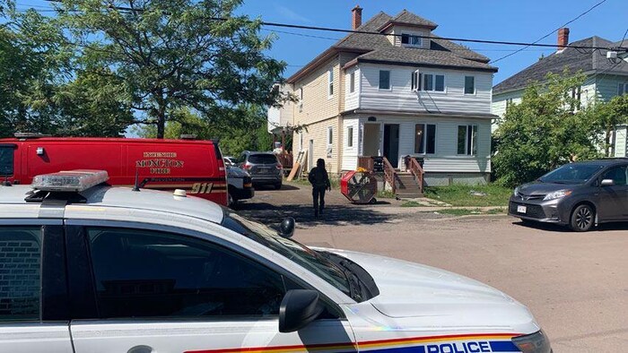 Un policier monte la garde devant une maison où se déroule une perquisition.