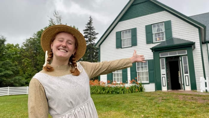Une jeune fille aux cheveux roux montre une maison.
