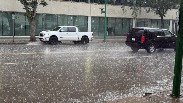 De la grêle tombe sur une rue d'un centre-ville. 