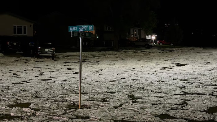 Une rue inondée d'eau sur laquelle flotte des morceaux de glace.