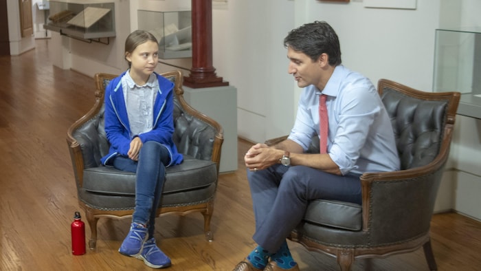Greta Thunberg et Justin Trudeau sont assis et discutent.