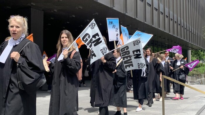 Des avocates brandissent des affiches indiquant qu'elles sont en grève.