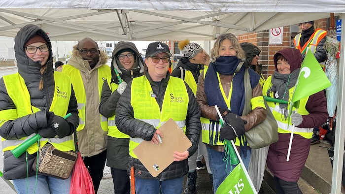Des manifestants portant des dossards du SFPQ sous une tente lors d'une manifestation à Rouyn-Noranda.