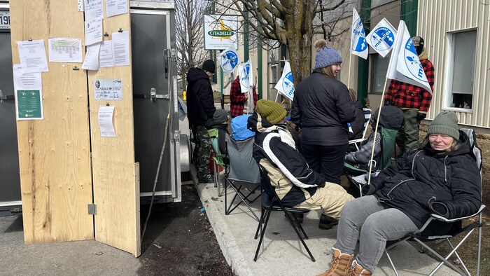 Des grévistes militent devant un bâtiment. 