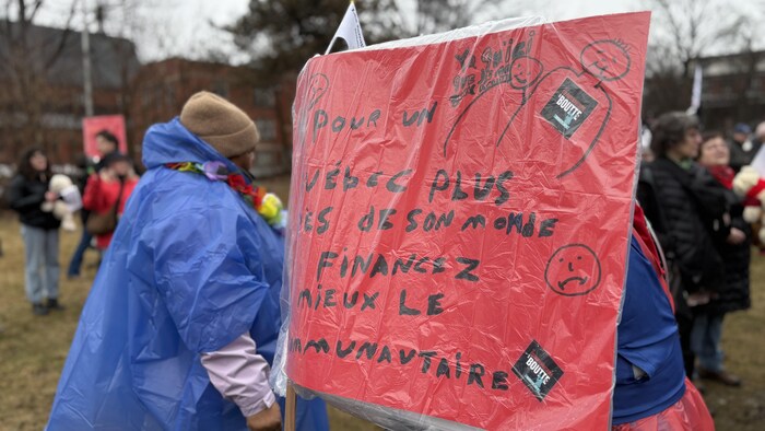 Une personne porte une affiche sur son dos.