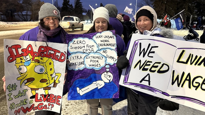 Des personnes dehors en hiver qui tiennent des pancartes de grève, à Edmonton en janvier 2025.