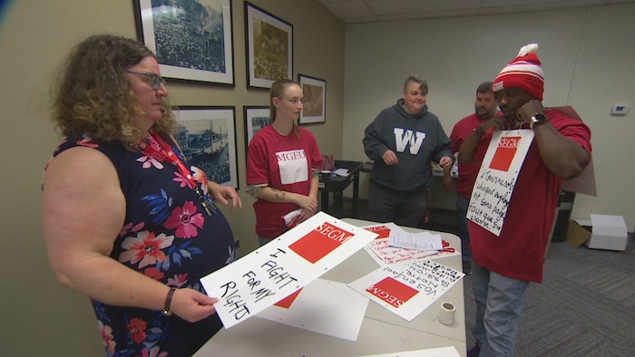Des personnes préparent des pancartes pour une grève et se trouvent au bureau syndical avenue Broadway, à Winnipeg, le 25 septembre 2022.