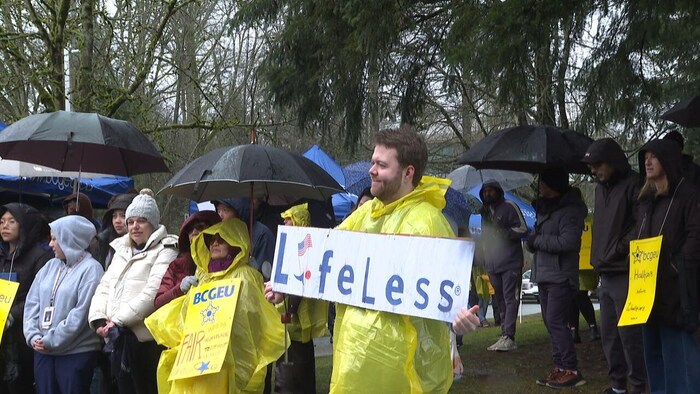 Des manifestants, tenant des parapluies et des pancartes.