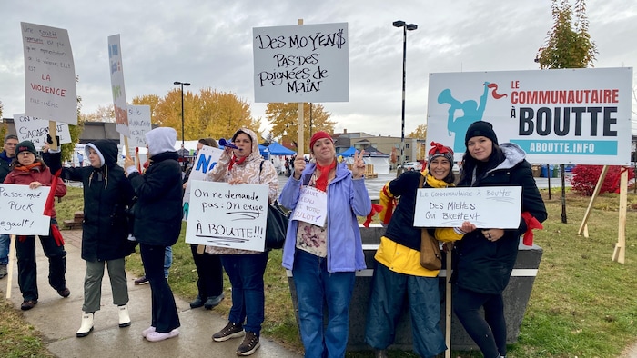 Des manifestants tiennent des pancartes mentionnant « Le communautaire à boutte ».