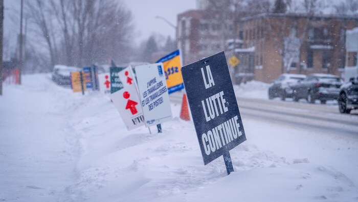 Des pancartes du syndicat FTQ sont plantées dans la neige. 