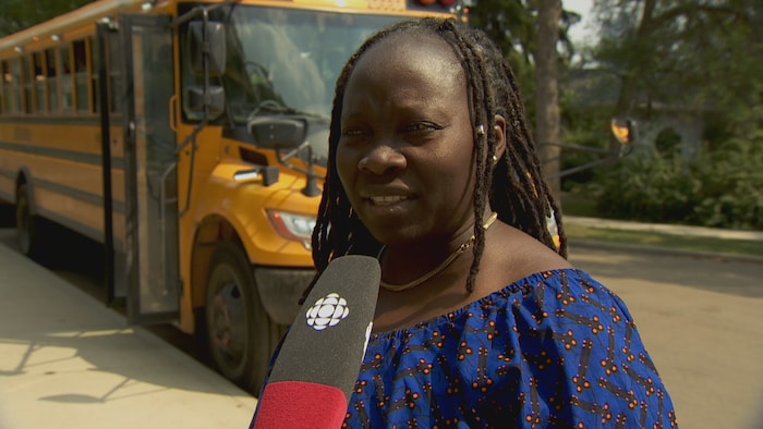 Anne-Marie Camara se trouve à l'extérieur devant un autobus scolaire.