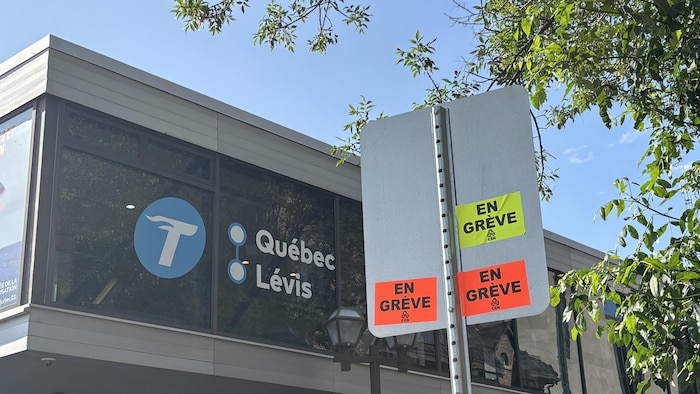 Des autocollants « en grève » sont collés au dos d'une affiche de signalisation, devant la gare fluviale de Québec.