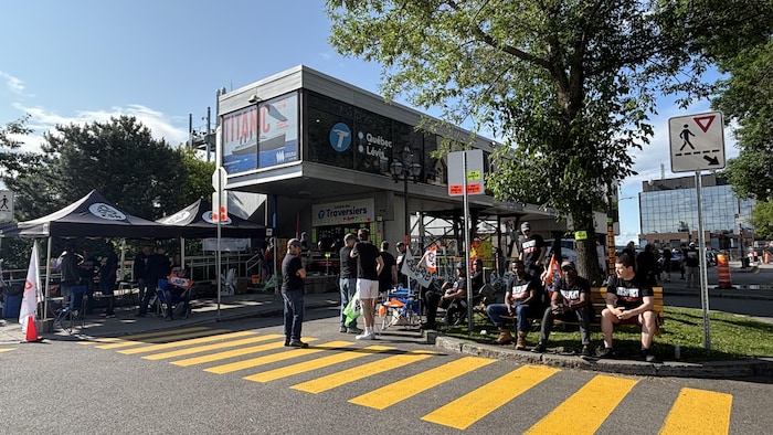Des syndiqués sont regroupés devant la gare fluviale de Québec. On voit des tentes et des fanions avec le logo de la CSN.