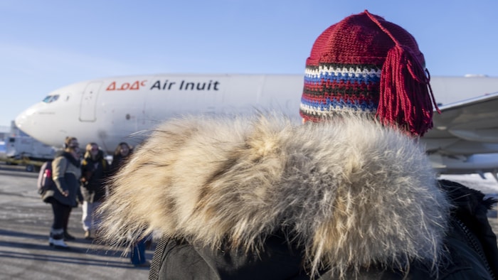 Des gens sont près d'un avion à l'extérieur et attendent son départ.
