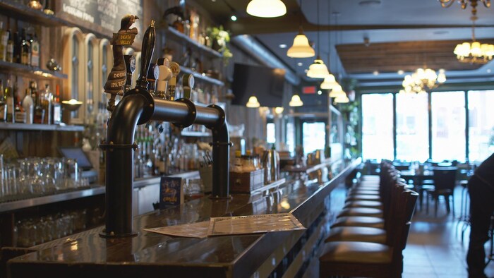 L'intérieur d'un bar-restaurant vide. La photo montre le long comptoir du bar et la rangée de chaise en attente de clients.
