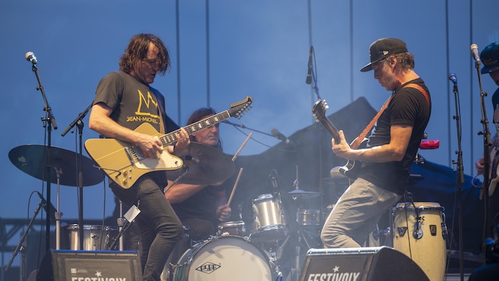 Deux guitaristes jouent en se faisant face.