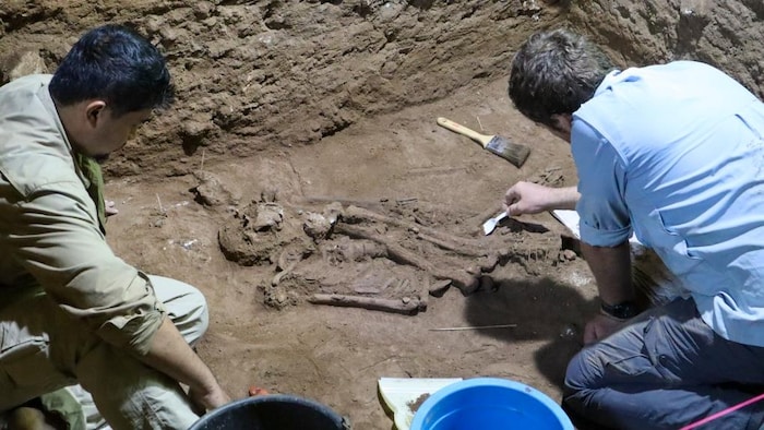 Deux anthropologues travaillent dans une grotte.