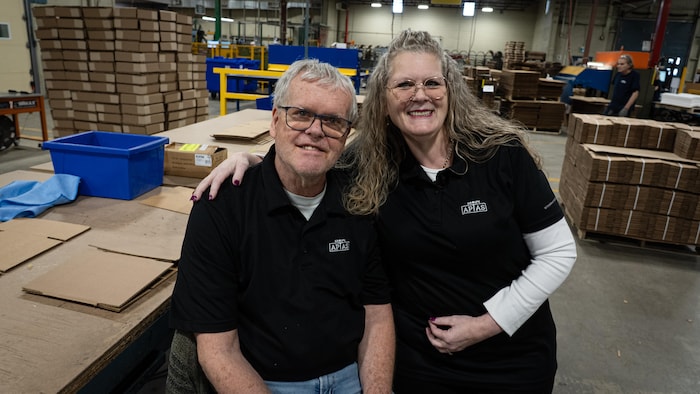 Un homme et une femme tout sourire dans une usine.