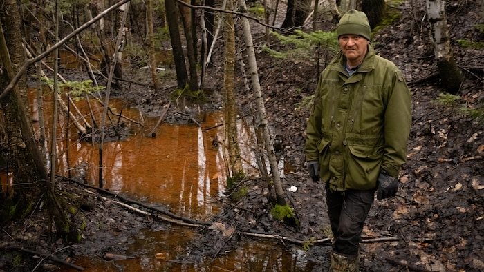 Michel Lafleur debout dans la tourbière à côté d’un étang. 