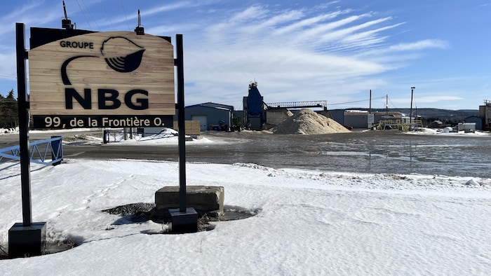 Affiche du groupe NBG devant un bâtiment et un tas de copeaux de bois.