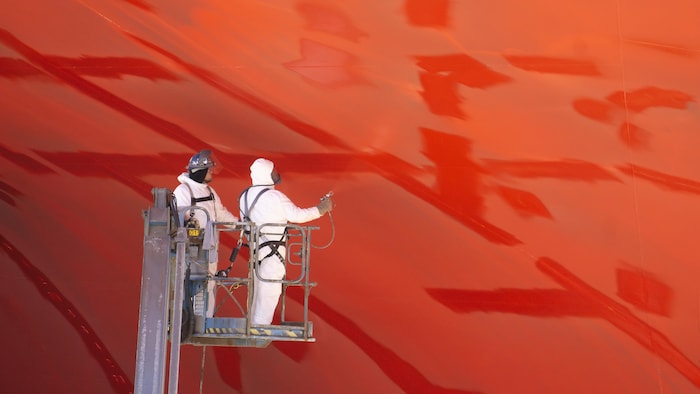 Des peintres au travail sous le navire.