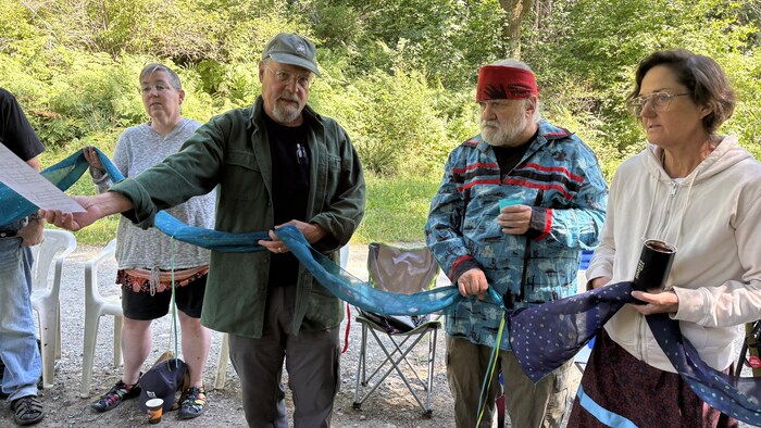 Des personnes tiennent un long fil de tissu et s'apprêtent à chanter.